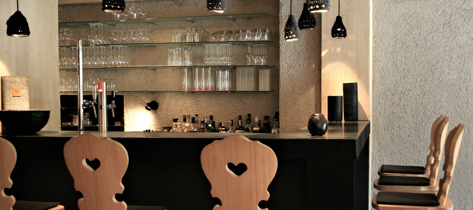 Bar-Regal mit Gläsern und Flaschen, Stühle mit Herz-Ausschnitt – MONTAFONLodge
