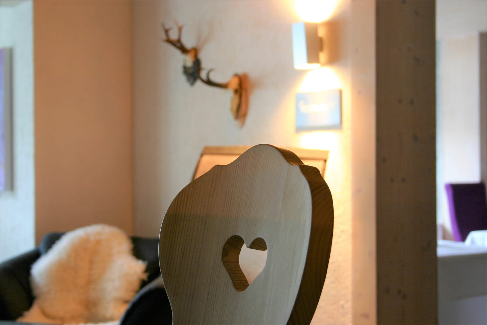 Stuhllehne mit Herz-Ausschnitt und Deko-Geweih an der Wand – MONTAFONLodge