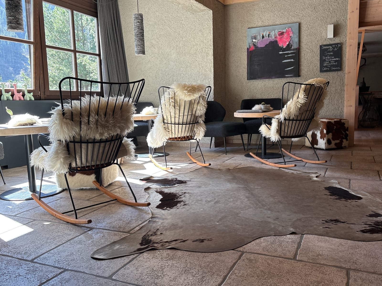 Lounge mit Schaukelsesseln und Schaffellen auf Steinboden – MONTAFONLodge