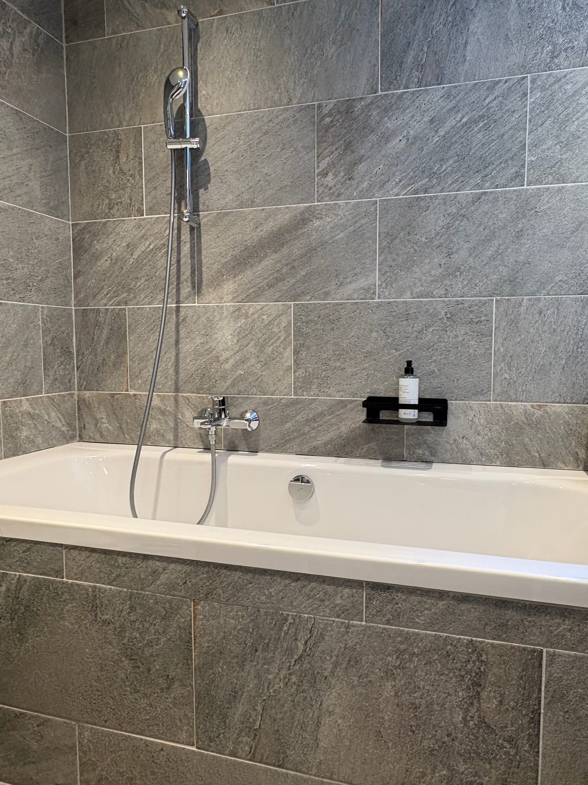 Badewanne mit Wandarmatur, Steinfliesen – MONTAFONLodge