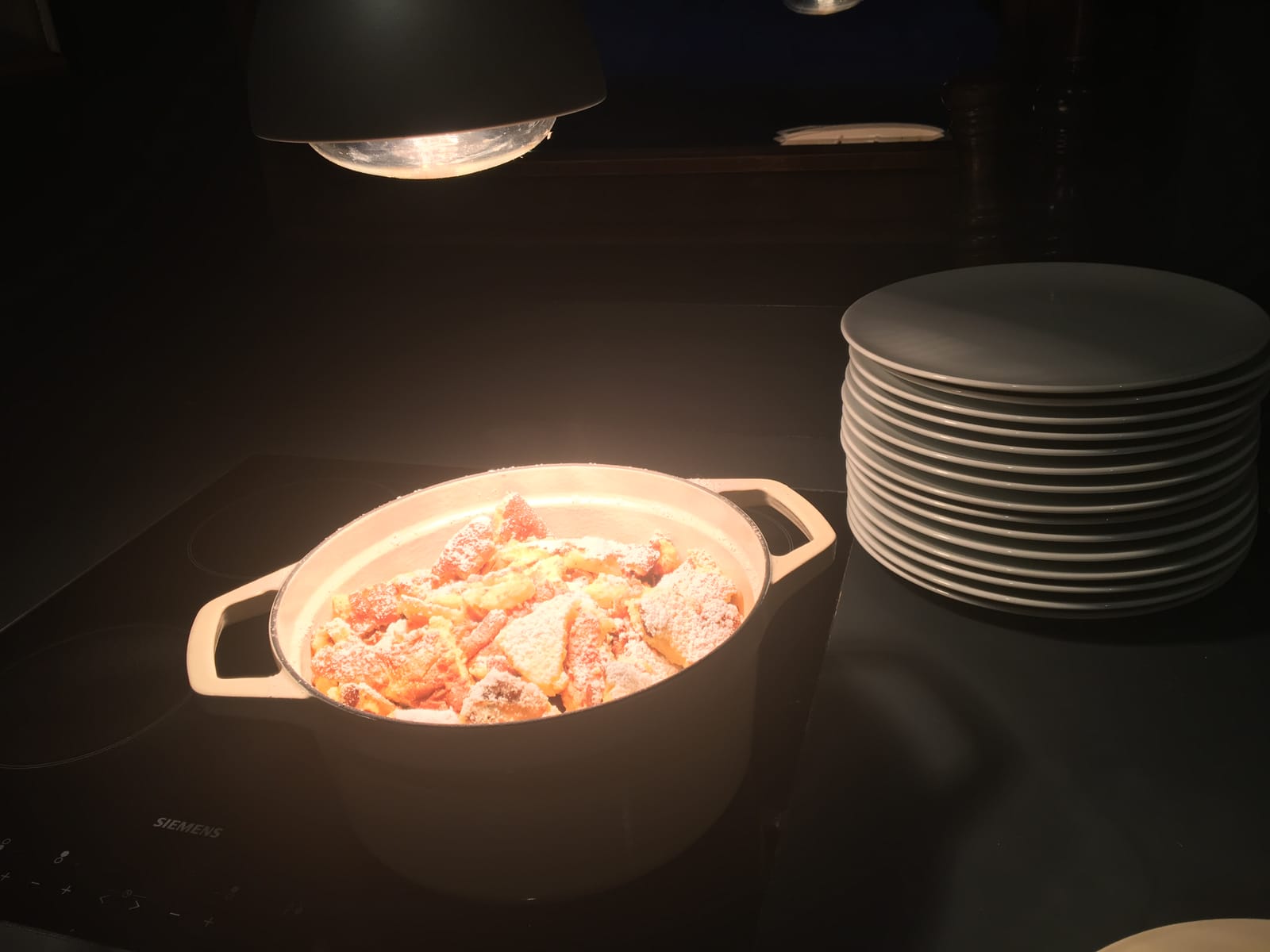 Gusstopf mit Lachs-Gericht unter Spot, daneben Tellerstapel – MONTAFONLodge