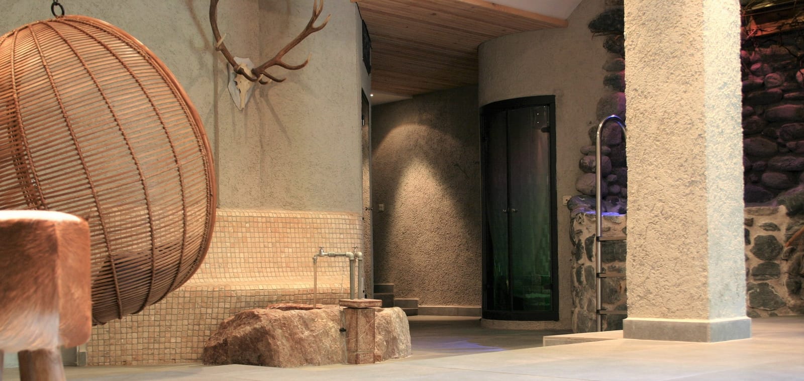 Rattan-Hängesessel mit Deko-Geweih am Sauna-Zugang – MONTAFONLodge