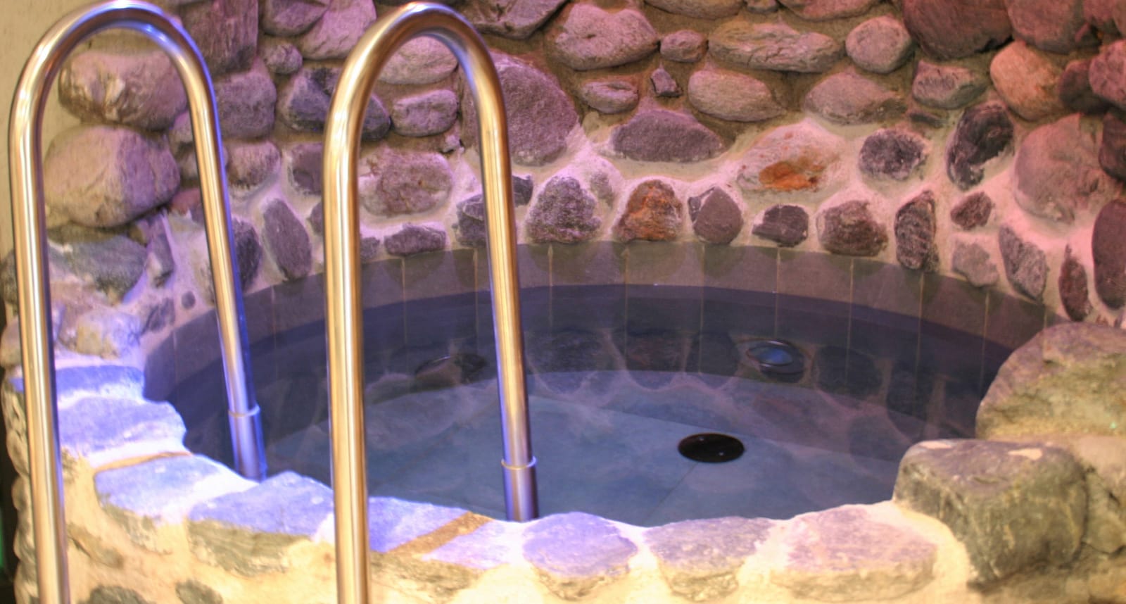 Beleuchteter Stein-Whirlpool mit Natursteinmauer – MONTAFONLodge