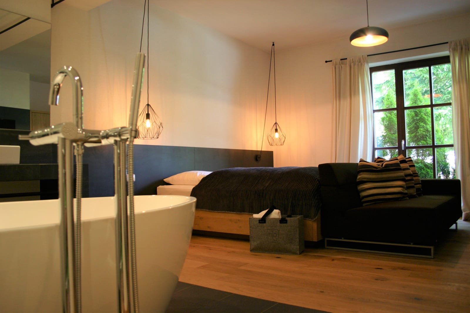 Freistehende Badewanne mit Standarmatur vor dem Bett – MONTAFONLodge
