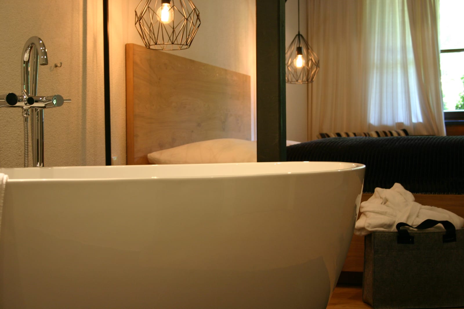 Freistehende Badewanne mit Holz-Kopfteil und Pendelleuchte – MONTAFONLodge