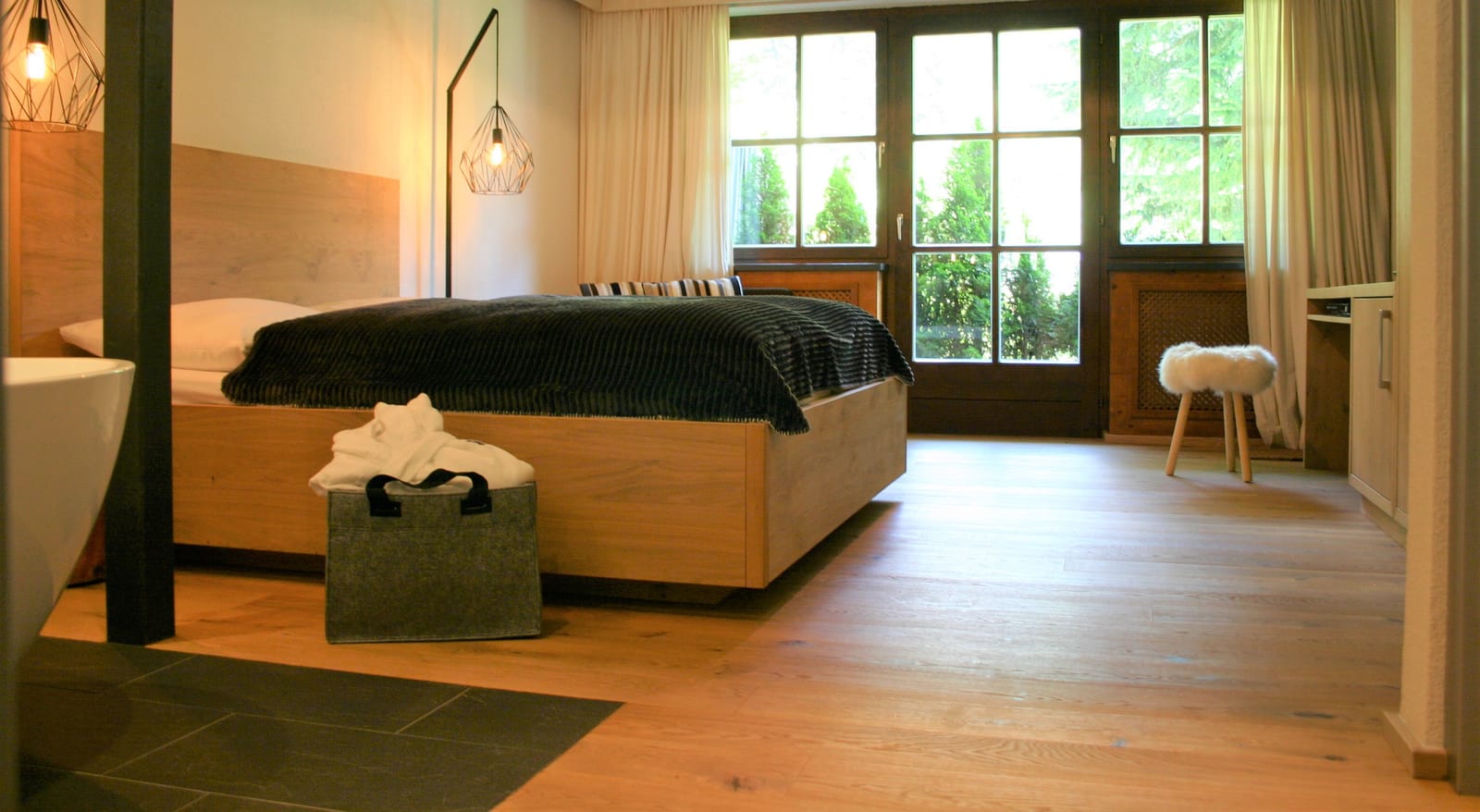 Doppelbett am Fenster mit Schaffell-Hocker und Deko-Tasche – MONTAFONLodge