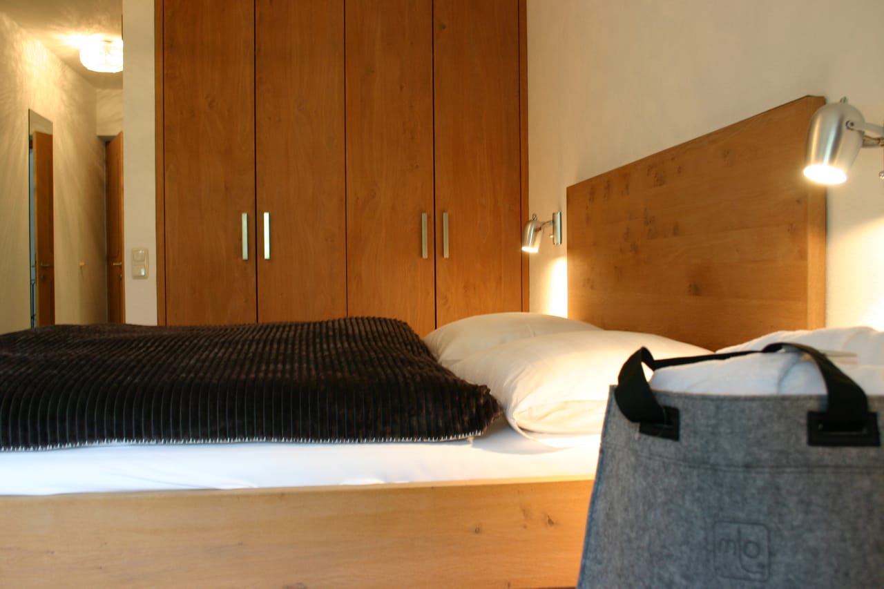 Small Doppelzimmer der MONTAFONLodge mit Doppelbett, Sitzbank und Balkontür